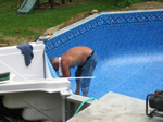 Here you should notice that the liner is completely installed around the pool and the step is NOT cut in yet. The step does not get cut in until after the step strips are installed and the water level is up near the bottom step. Also note the vinyl liner is sealed against the step with duct tape to help create a vacuum lock during the air evacuation process of pool liner installation.