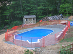 This onground pool is full of water and a temporary fence is used.